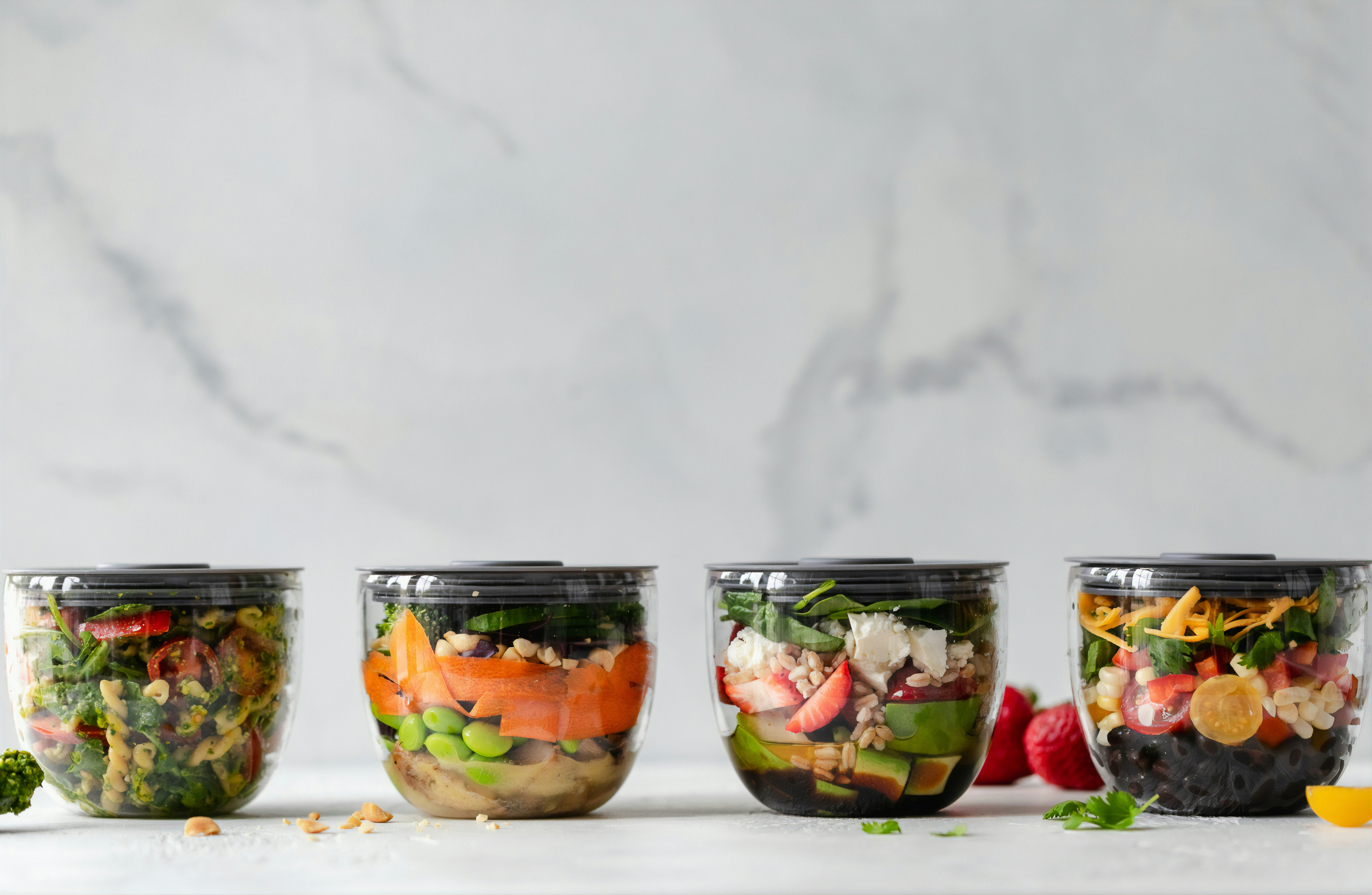 clear meal prep containers with colorful vegetables and a marble background