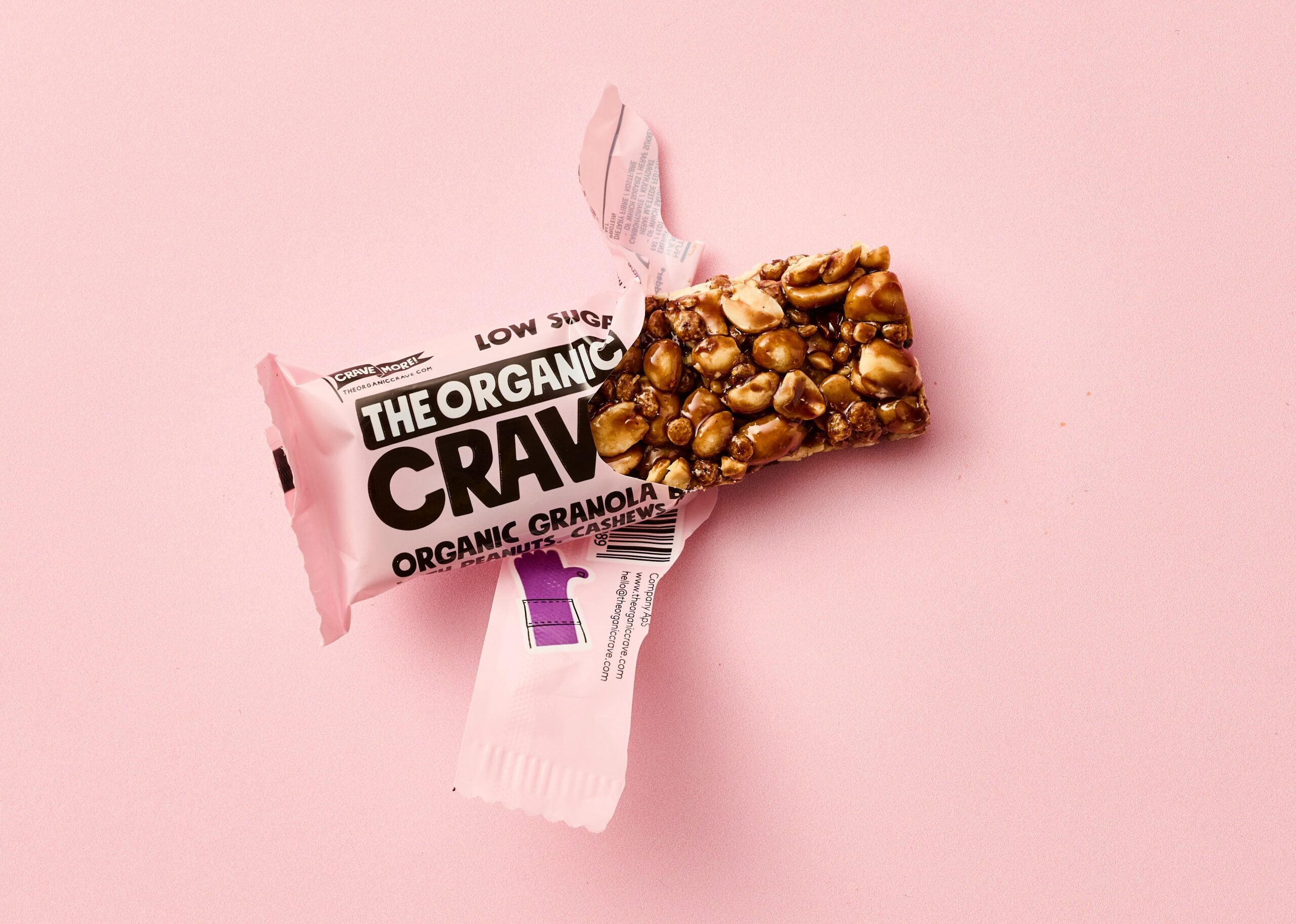 half opened granola bar in a pink wrapper on a pink background